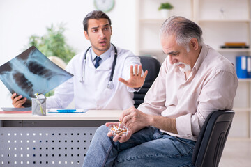 Obraz premium Young male doctor and old patient in antismoking concept