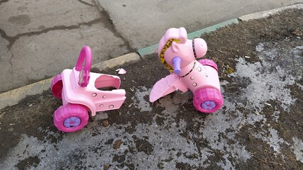 broken toy. baby pink horse on wheels broke on the road