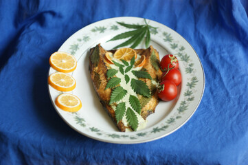 cannabis food. classic cannabis leaf lies on grilled fish. homemade grilled fish food with young leaves of marijuana