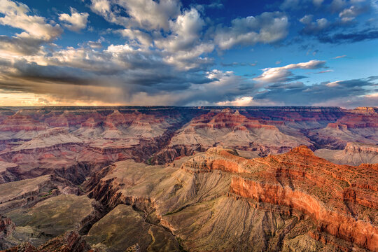 Sunset with stormy clouds sweeping across the vast landscape at the Grand Canyon South rim, Arizona.