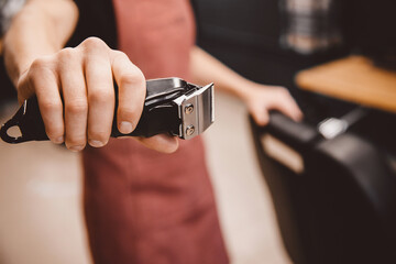 Barber holds hair clipper in modern barbershop for men, brown retro