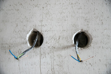 Electrical work with rough finish, electrician connects and mounts copper wires for outlet in...