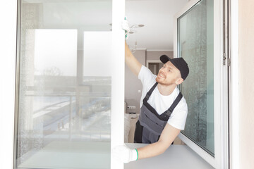 Worker man installs plastic windows and doors with double-glazed white