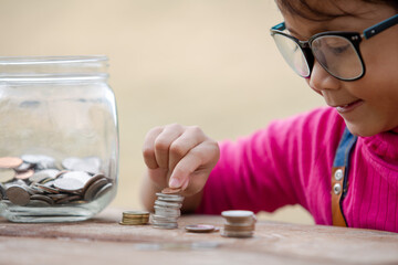Little girl and pile coin for saving. money saving concept.