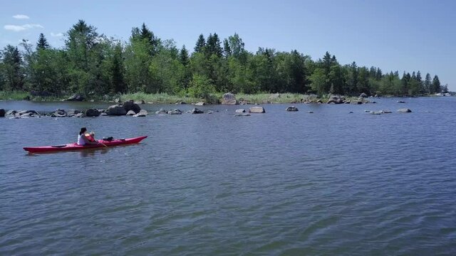 Travel Finland, Tracking drone shot of mother and child exploring tranquil Nordic nature by kayak