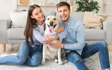 Young happy friends with dog sitting in living room