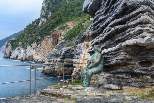 Statue of Mater Naturae, Mother Nature sitting on rocks of coast of Portovenere or Porto Venere town on Ligurian coast. Italy