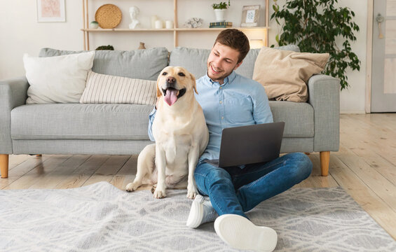 Young man at home with laptop and happy dog