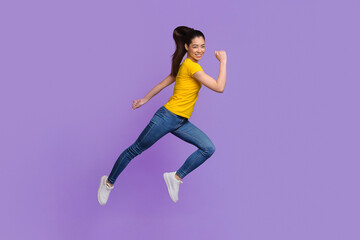 Fototapeta na wymiar Happy Asian Girl Jumping In Air Over Purple Background, Portrait In Motion