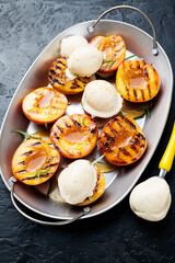 Summer dessert. Ripe grilled peaches with honey and ice cream on black background. 
