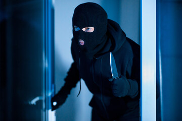 Killer breaking in an apartment holding blade