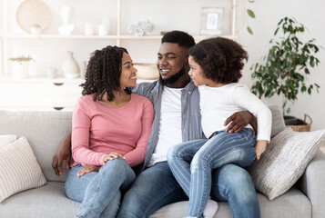 Portrait of happy black family resting together on couch at home
