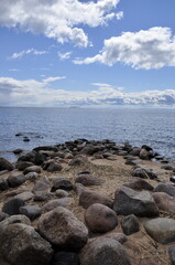 Fototapeta na wymiar Rocky beach and white clouds in a blue sky.