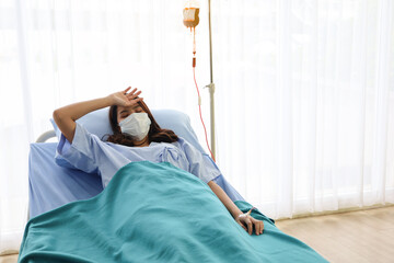 A patient woman wear face mask and cure on bed and covid-19 emergency treatment in a hospital room,...