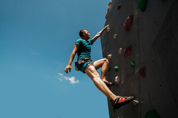 Sportsman climber on steep rock, climbing on artificial wall. Extreme sports and bouldering concept. © Victoria VIAR PRO