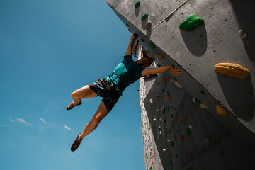 Sportsman climber on steep rock, climbing on artificial wall. Extreme sports and bouldering concept.