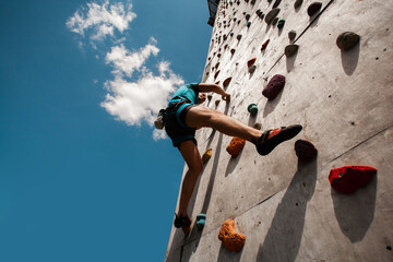 Sportsman climber on steep rock, climbing on artificial wall. Extreme sports and bouldering concept.