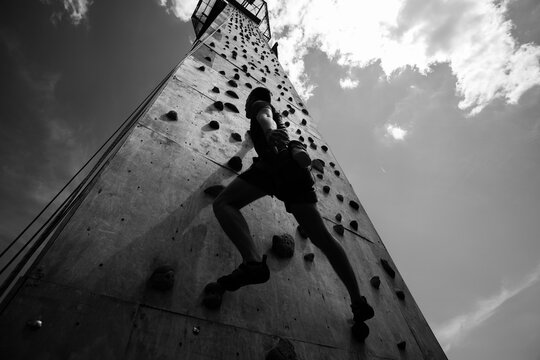 Sportsman climber on steep rock, climbing on artificial wall. Extreme sports and bouldering concept.