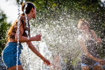 Teenagers playing in the fountain on a hot summer day