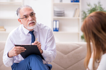 Fototapeta premium Young woman visiting old male doctor psychologist