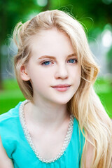 Portrait of a young blonde girl in a turquoise dress