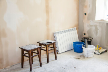 Repair work in the apartment. Concept of home improvement or renovation. Material for repair and two stools