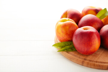 Nectarines on a cutting board on white background.