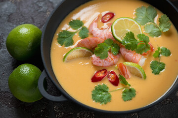 Thai-style soup with prawns, pumpkin, coconut milk, red chili, lime and coriander, selective focus, studio shot