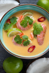 Closeup of thai soup with prawns, pumpkin, coconut milk, lime, red chili and coriander, vertical shot, top view