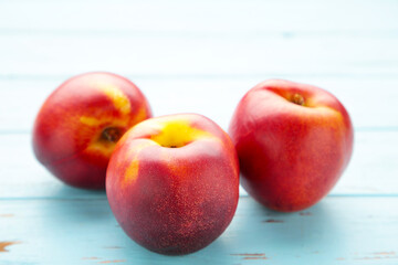 Many fresh nectarines on blue wooden background.