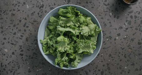 kale leaves in blue ceramic bowl on concrete background