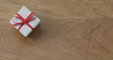 Fototapeta na wymiar top view gift box with red ribbon on oak table