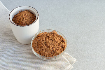 Carob powder in small saucer and in clay jar on the table