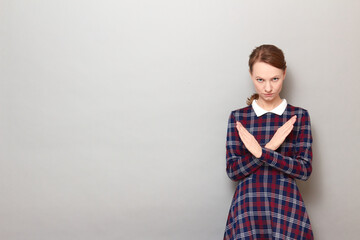 Portrait of serious girl making cross with hands, showing stop gesture