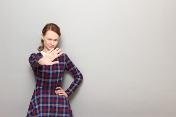 Portrait of annoyed girl showing palm at camera and covering her face