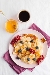Tiny pancakes with berries, honey, coffee. Pancake cereal. The concept of Breakfast, food trends. Copy space.