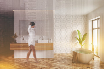 Woman walking in white honeycomb tile bathroom