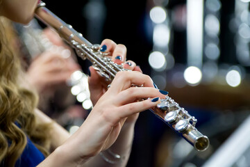 Hands holding a flute. Girl musician plays the flute.