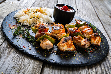 Grilled shashlik and white basmati rice on black stone plate on wooden table
