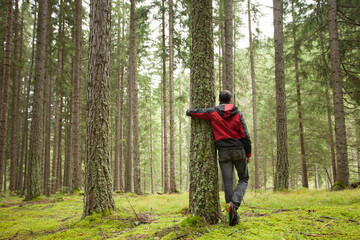 a man hugging a tree in the woods