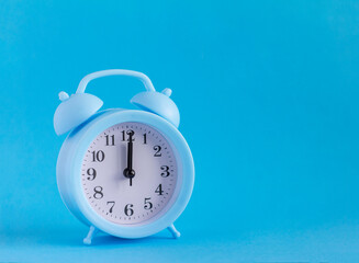 Small blue alarm clock on a blue background.