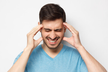 Naklejka premium Close up portrait of man touching temples with closed eyes, trying to relieve strong headache, feeling stressed and exhausted, isolated on gray background
