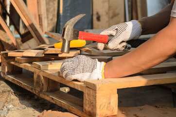 The carpenter is nailing the wood.
