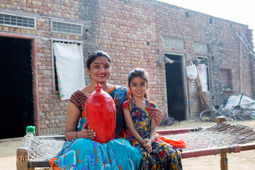 Rural mother with daughter saving money in piggy bank