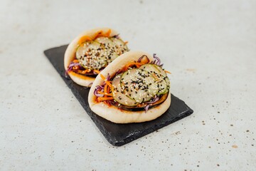 Closeup shot of a steamed bao bun with cucumber covered with sesame seeds