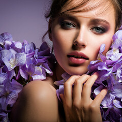 Pretty woman with bright makeup. Beautiful white girl with flowers. Stunning brunette girl with big bouquet  of hydrangeas. Closeup face of young beautiful woman with a healthy clean skin.