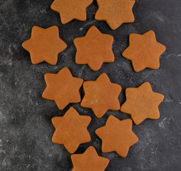 Various christmas gingerbread cookies on dark table with flour