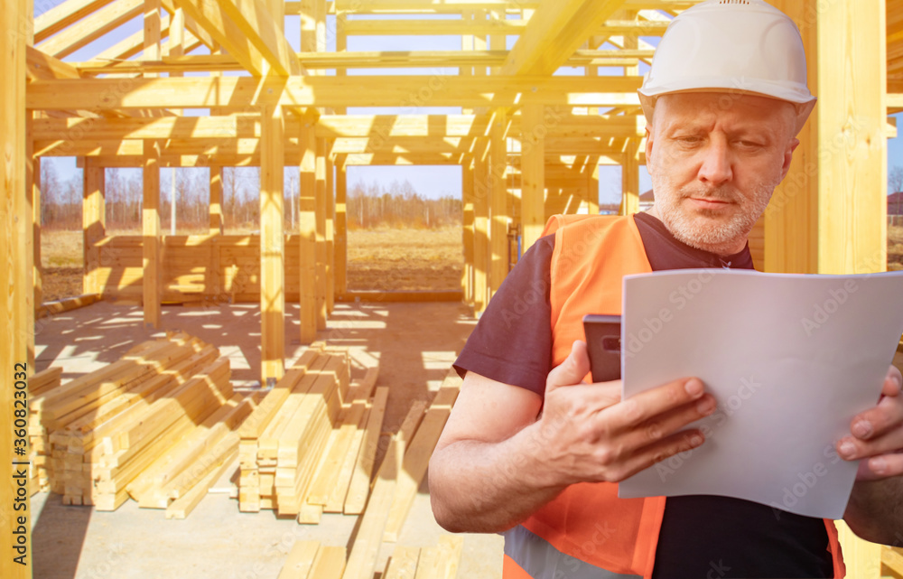 Poster construction of cottages. builder with documents and phone on the background of the frame of the hou