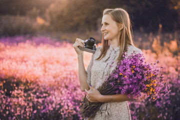 girl photographer in a sunny meadow with a retro camera takes pictures