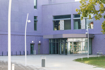 Modern purple building with lawn and trees, lights around. Entrance to low-rise business center